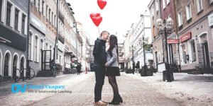 A couple kissing holding red heart balloons