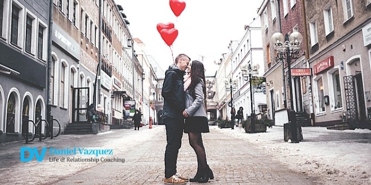 A couple kissing holding red heart balloons